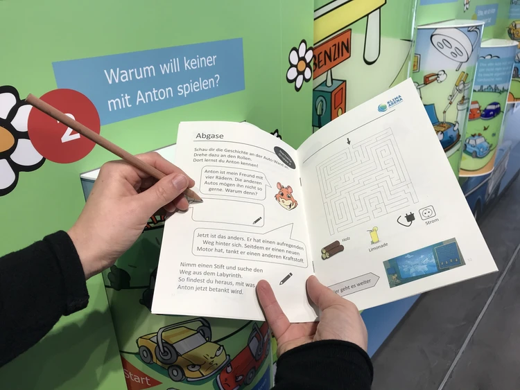 Eine Person h&auml;lt ein Klima-Rallye-Heft in der Hand und f&uuml;llt darin eine Aufgabe aus.