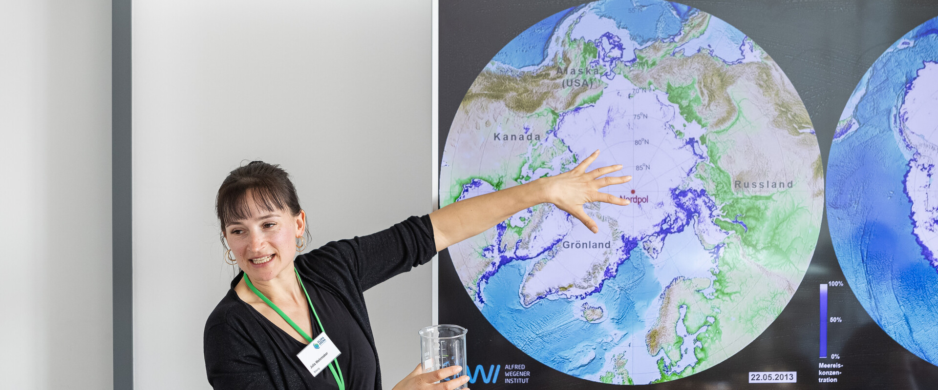 Bildungsmitarbeiterin zeigt an Schaubild das Eisschild in der Arktis.